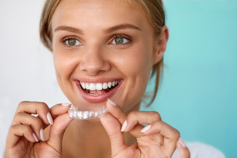 woman holding Invisalign retainer near her mouth