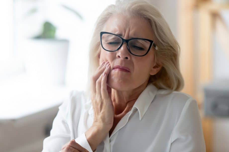 mature woman holder her jaw in pain