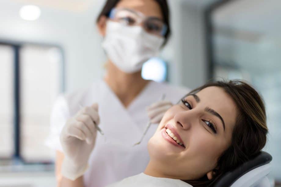 woman in dental chair with dental assistant to her side